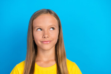 Photo of smart clever little lady look empty space think ideas wear yellow t-shirt isolated blue...