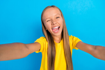 Photo of crazy influencer little lady make selfie wink eye show tongue wear yellow t-shirt isolated blue color background