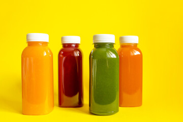 Fresh juices or smoothies of fruits and vegetables in bottles on a yellow background. The concept of a healthy diet, diet or detox. Flat lay, top view