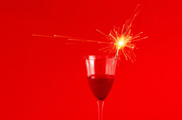 Sprinklers shoot on a red background in a glass of red wine, Christmas
