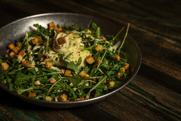 Organic vegetable salad with arugula leaves with pesto sauce and pieces of fried bread with parsley and garlic accompanied by pesto sauce and served in a metal container