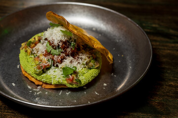 Corn cake or taco stuffed with avocado and different organic vegetables with a lime and cinnamon dressing and cheese sprinkled on top