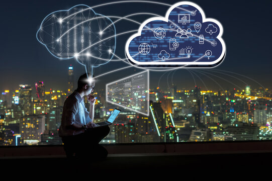 Asian businessman sitting and using the laptop and working with brain and virtual screen connecting with cloud technology over the cityscape background at night time, Business and technology concept