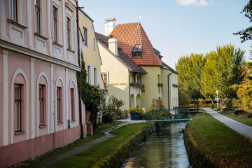 Trebon, South Bohemia, Czech Republic, 9 October 2021: Narrow picturesque street with colorful buildings in historic center of medieval city, water channel called gold drain at sunny day