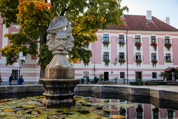 Trebon, South Bohemia, Czech Republic, 9 October 2021: Castle Courtyard, Renaissance chateau with sgraffito mural decorated plaster at facade, fountain with sculpture of bird perched on three heads
