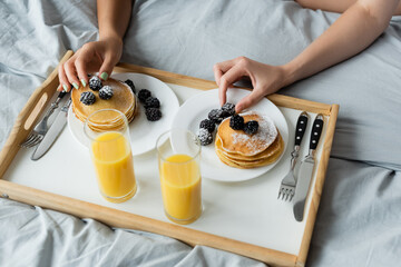 Fototapeta na wymiar cropped view of women reaching blackberries on pancakes