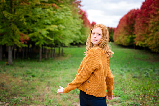 Happy tween girl surrounded by fall color trees.