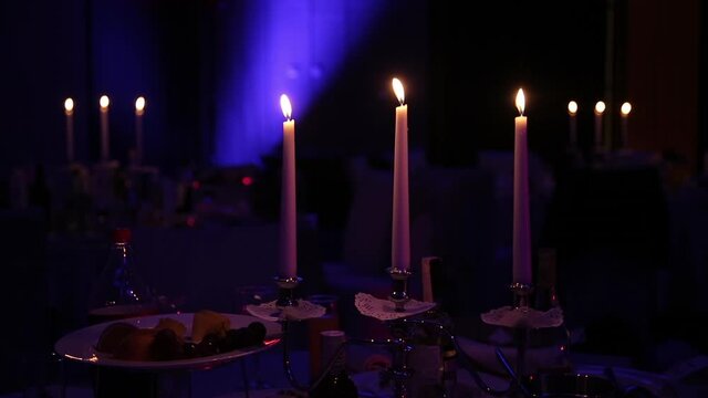 Festive banquet by candlelight. Dinner in a restaurant by candlelight in the spotlight. The atmosphere of celebration and fun.