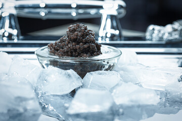 Black caviar. Black sturgeon caviar in a glass bowl on a silver tray with ice.