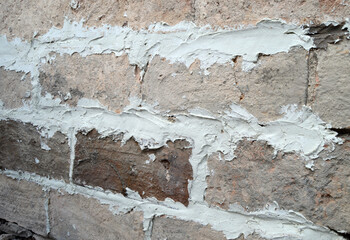 Emparchado con mortero de cal de un viejo muro de ladrillo de taco. Trabajos de albañilería en un muro de ladrillos rústicos macizos