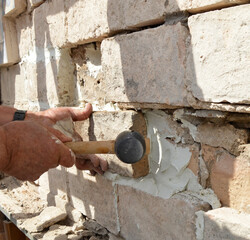 Albañil constructor colocando ladrillos de taco en un muro con martillo de goma. Trabajos de...