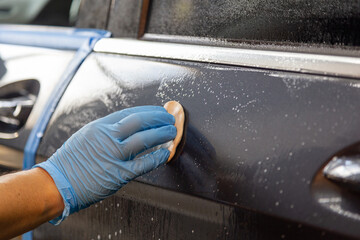 Man cleaning car with a clay bar to remove dust
