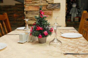 Christmas table setting with christmas tree and wooden chairs in russian restaurant interior