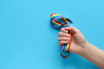 Rainbow ribbon in child hand. Blue mint paper backgrounds. Thank you NHS workers, doctors and...