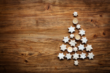 Christmas tree decorated from cinnamon stars and candlelights on brown vintage wood. Top view background with space for text.
