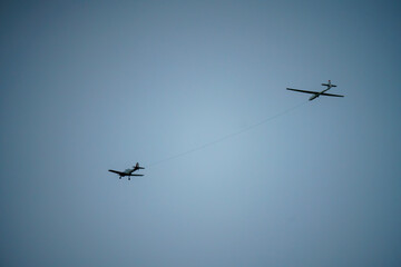 a 1950s De Havilland DHC-1 Chipmunk tows a glider overhead in a deep blue winter sky