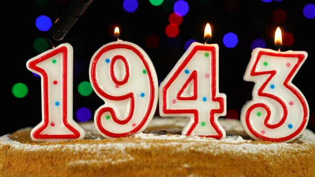 Birthday cake with white burning candles in the form of number 1943
