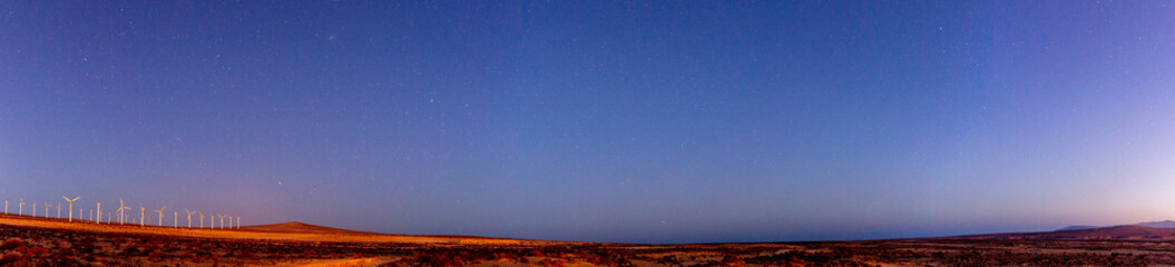 Night panorama of the desert with wind generators and the starry sky, USA