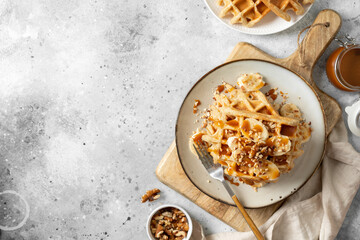 Banana waffles with walnuts and salted caramel in a plate on a culinary background