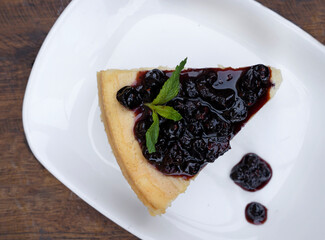Desserts. Top view of a slice of Cheesecake with mascarpone cheese and berries dressing, in a white dish on the wooden table. 
