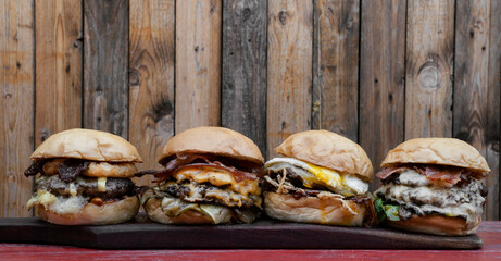 Monster burgers. Closeup view of four multilayer burgers on the restaurant table with a wooden...
