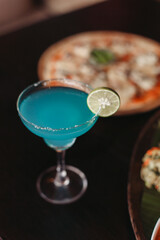 Blue cocktail and pizza on the table