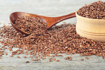 Wooden spoon and wooden bowl with flax seeds on wooden table