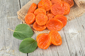 Dried apricots with green leaves on rustic wooden background