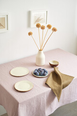 Modern dining table setting. Only natural materials - earthenware, linen textiles, dried flowers. Side view.