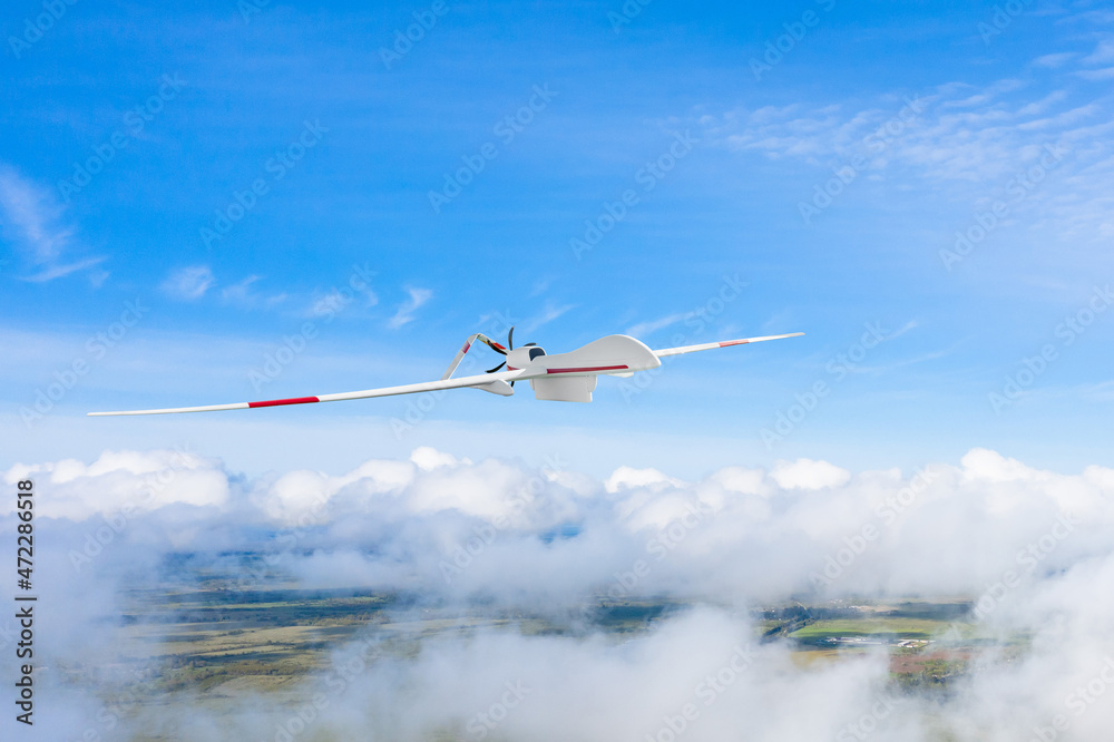 Wall mural Military drone flies in the clouds on the surface of the earth.