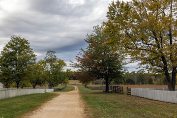 Fototapeta na wymiar Dirt path between two fences on a farm field in rural Virginia on a cloudy Autumn day.
