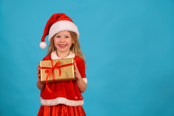Happy merry Christmas child in Santa hat hold gift. beautiful girl smiles laughs. Congratulate celebration. Jolly Santa Claus preparing box gold red bow. Happy New Year. Place for text. Copy space. 