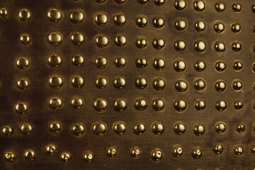 Brown wood background with metal gold buttons arranged in even rows - 472290164