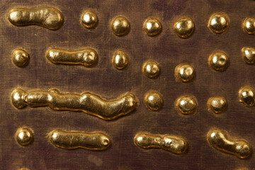Round drops and drips of gold metal on the surface of the board - 472290192