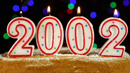Birthday cake with white burning candles in the form of number 2002