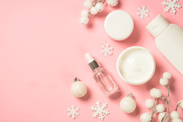 Obraz na płótnie Canvas Winter cosmetic, skin care product. Cream, serum, tonic with winter decorations. Top view on pink background with copy space.