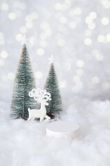 Podium or pedestal mok-up for cosmetics in the snow with a christmas tree on bokeh background vertical format