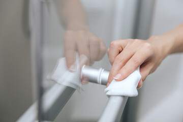 Obraz na płótnie Canvas Cleaning glass door handles with an antiseptic wet wipe. Woman hand using towel for cleaning home room door link. Sanitize surfaces prevention in hospital and public spaces against corona virus