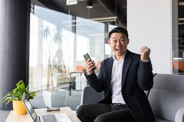 Successful business man, rejoices in victory and successful sales contract, smiles looks at camera in modern office, boss SEO celebrates winning