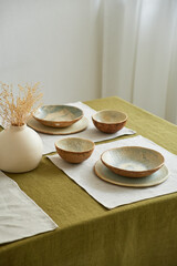 Modern dining table setting. Only natural materials - earthenware, linen textiles, dried flowers. Top view.