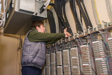 The technician is laying communication lines by conducting internet telephony. servicing the Automatic Telephone Station in the server room.