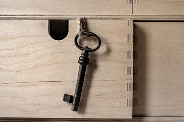 Old iron key hanging on a rope from a wooden box