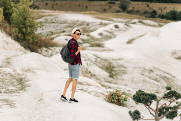 Wanderer with a backpack in the mountains. The tourist stands against the background of the mountain. Mountain travel