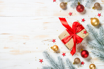 Christmas background at white. Christmas present box with red ribbon and holiday decorations. Top view with copy space.