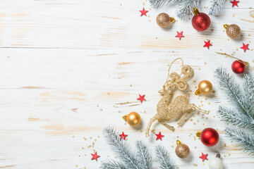 Christmas background with fir tree, red and golden holiday decorations. Top view at white wooden table with copy space.