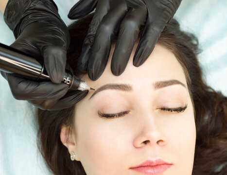 Permanent makeup. Permanent eyebrow tattoo. Cosmetologist applying permanent makeup on eyebrows - eyebrow tattoos. Tattooing. Microblading.