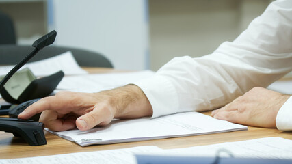 A man in a white shirt presses the video camera and microphone button during a video chat or online conference. Without a face. Selective focusing