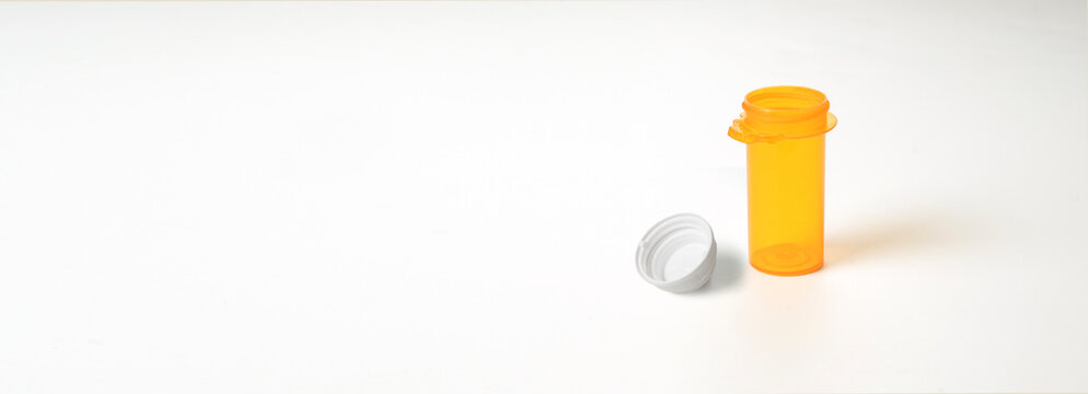 Empty prescription bottle with lid off on white background