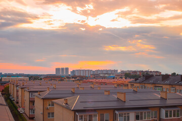 A cottage village with identical roofs against the background of dawn. Construction and real estate