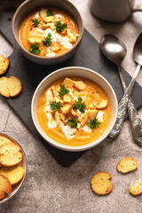 autumn lunch: pumpkin cream soup with cream and crackers. serving lunch for two. photo on gray background